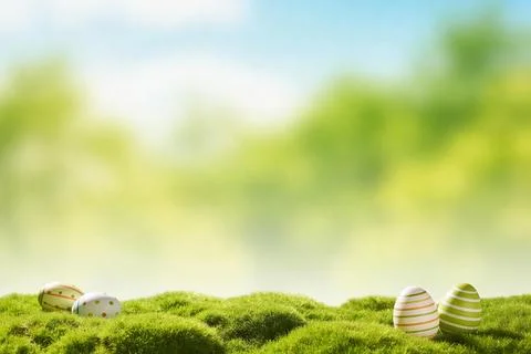 Decorated Easter eggs resting on lush green moss with a soft bokeh background Stock Photos