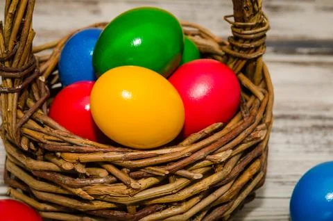 Decorated Easter eggs in wicker basket on rustic background, close up view Stock Photos