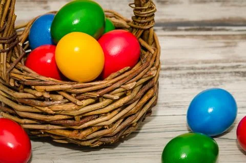 Decorated Easter eggs in wicker basket on rustic background Stock Photos