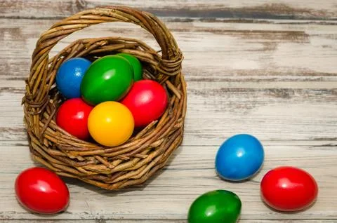 Decorated Easter eggs in wicker basket on rustic background, top view Stock Photos