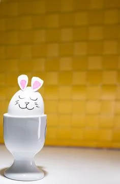 Decorated eggs placed in white egg cups, each egg featuring a hand-drawn ha.. Stock Photos