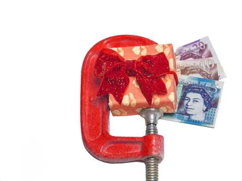 Decorated gift box in red wrapped paper and bow in clamp with label and money Stock Photos