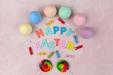 Decorated Happy Easter text with painted eggs and lollipops on pink backgroun Stock Photos