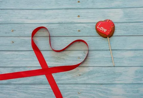 Decorated heart shape cookie on a stick with red tape in form of heart on blu Stock Photos