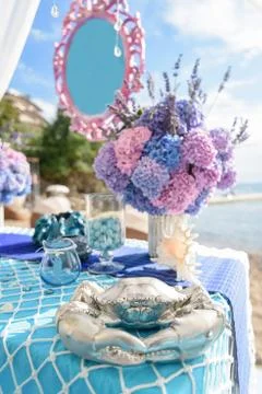 Decorated holiday table with crab, shells, flowers Stock Photos