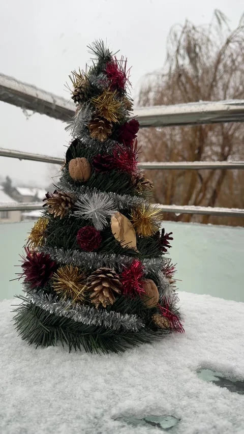 Decorated mini christmas tree outdoors on snowy surface during winter sleet weat Stock Footage 321822551