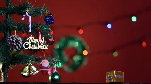 Decorated mini Christmas tree on a table with red background and lights bokeh Stock Footage 167191720