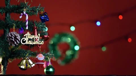 Decorated mini Christmas tree on a table with red background and lights bokeh Stock Footage 167191736