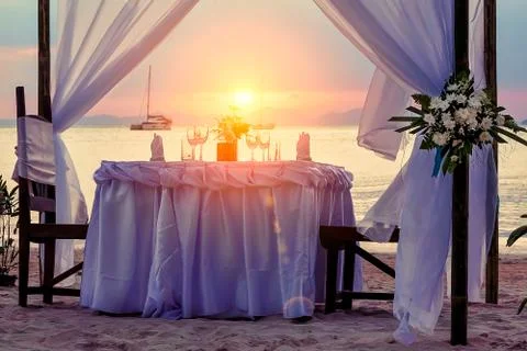 Decorated for a romantic dinner table on the sandy beach. Against the backdro Foto stock