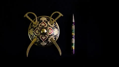 Decorated round sword and shield and pen isolated in black background with co Stock Photos