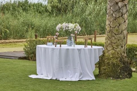 Decorated round table with flowers prepared for outdoor celebration Stock Photos