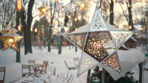 Decorated star lanterns glow in winter park with snow covered tables and ch.. Stock Footage 339260040