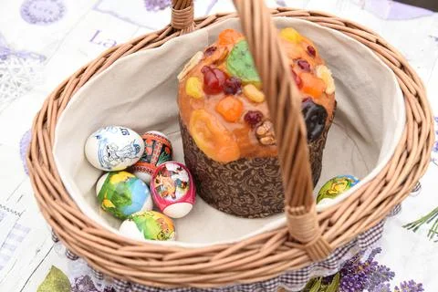 Decorated wicker Easter basket with Easter cake, painted eggs, treat Stock Photos