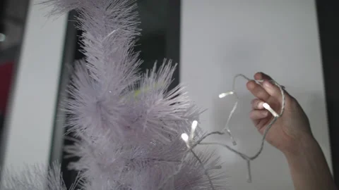 Decorating an amazing white christmas tree with clear lights. Stock Footage 138103936