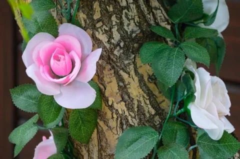 Decorating of artificial flowers with a tree trunk. Close-up. Stock Photos