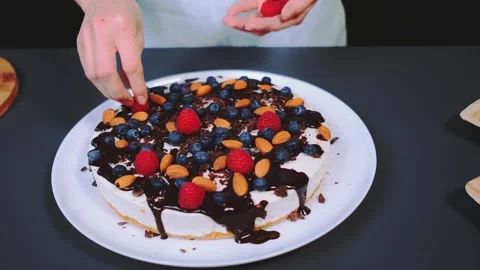 Decorating a berry and almond cake with chocolate sauce indoors Видео 342869690