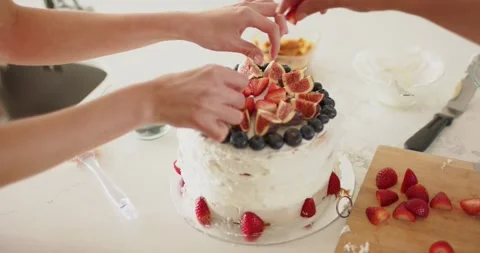 Decorating cake on marble counter two women placing grapes arranging figs and Stock Footage 337159931