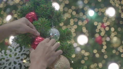 Decorating a Christmas tree. hands decorating christmas tree with red baubles Stock Footage 257292438