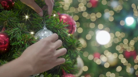 Decorating a Christmas tree. hands decorating christmas tree with red baubles Stock Footage 257335141
