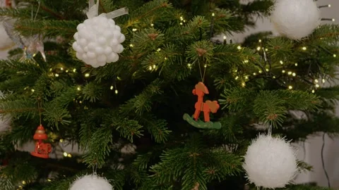 Decorating a Christmas tree with ornaments and lights in a cozy home Stock Footage 346698127