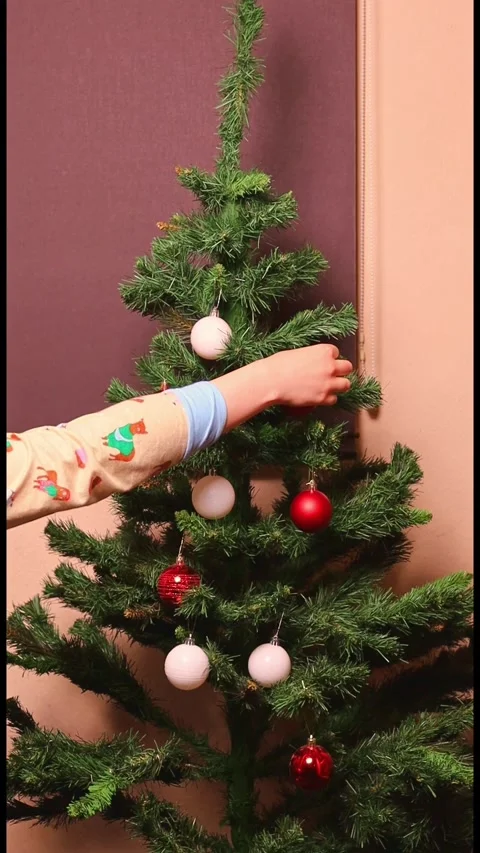 Decorating a Christmas tree with red and white ornaments in a living room Stock Footage 323214582