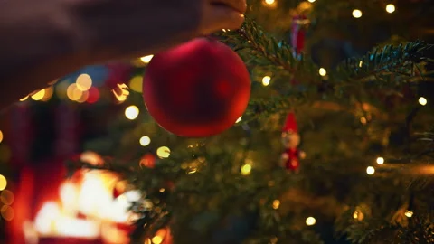 Decorating Christmas Tree with Red Bauble by Burning Fireplace in in Slow Motion Stock Footage 208931207