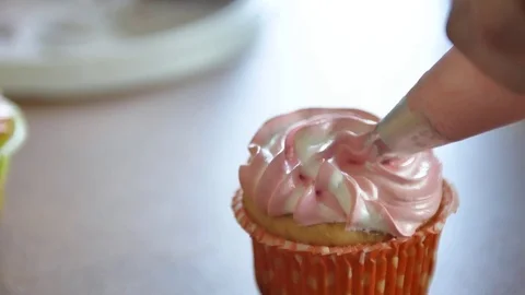 Decorating cup-cake with cream. Using cooking bag, confectioner making Stock Footage 76940414