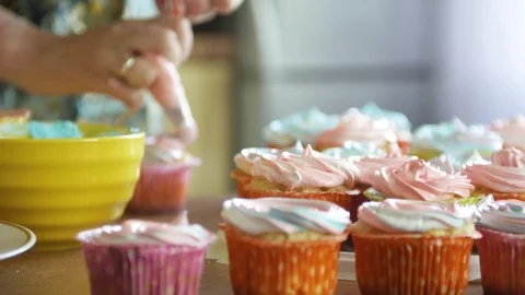 Decorating cup-cake with cream. Using cooking bag, confectioner making Stock Footage 77059871
