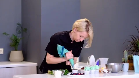 Decorating cup-cake with cream. Using cooking bag, confectioner making Stock Footage 109575408
