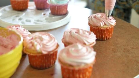 Decorating cup-cake with cream. Using cooking bag, confectioner making Stock Photos