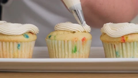Decorating cupcakes by piping on icing. Видео 144908107