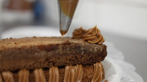 Decorating with Dulce de Leche Dressing with a Pastry Bag in a Vanilla Cake Stock Footage 129049451