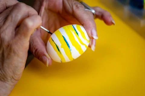 Decorating easter eggs with yellow and blue paint for the Easter holidays. Stock Photos