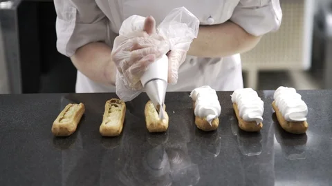 Decorating eclairs with cream. Using cooking bag, confectioner making eclairs 스톡 동영상 96143390