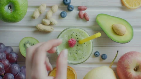 Decorating fruit smoothie with raspberries Stock Footage 99813655