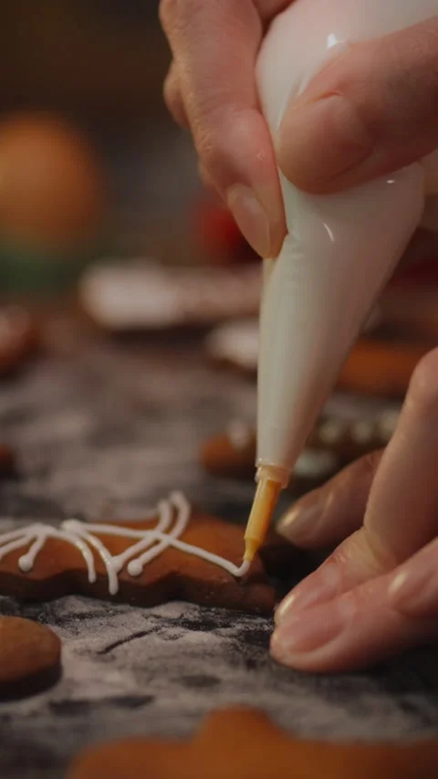 Decorating gingerbread cookies with icing during holiday preparations at hom Stock Footage 331541609