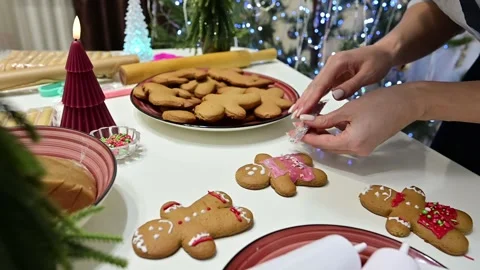 Decorating gingerbread men at a Christmas tree with beautiful hands Stock Footage 346557644