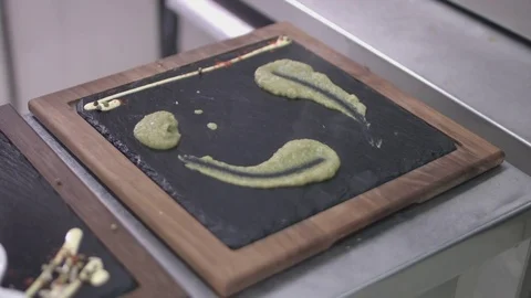 Decorating a granite serving plate with broccoli paste. Restaurant service Stockbeeldmateriaal 72315090