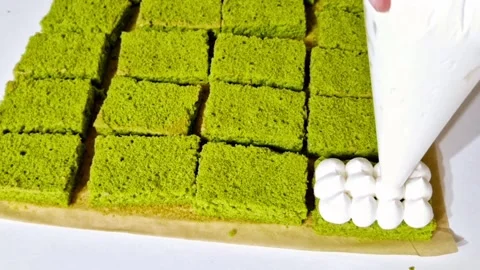 Decorating green matcha sponge cake with white cream piping for layer assembly Stock Footage 327258834