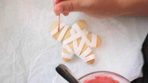 Decorating Halloween biscuits in a mummy shaped shortcrust pastry Stock Footage 117071972