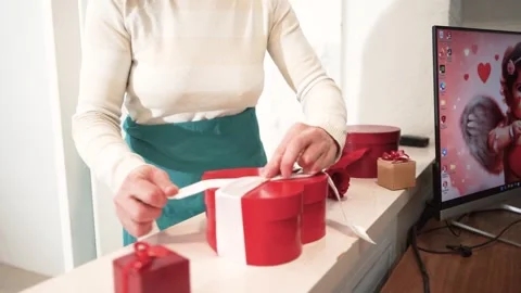 Decorating a holiday gift box in the shape of a heart in a gift Stock Footage 264290275