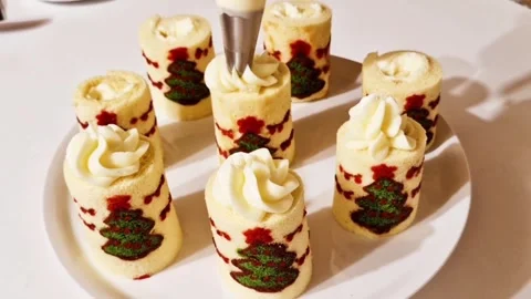 Decorating mini christmas tree swiss roll cakes with white whipped cream icing Stock Footage 327259416