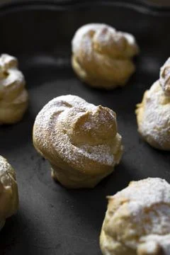 Decorating profiteroles with powdered sugar. Eclairs with icing sugar Stock Photos