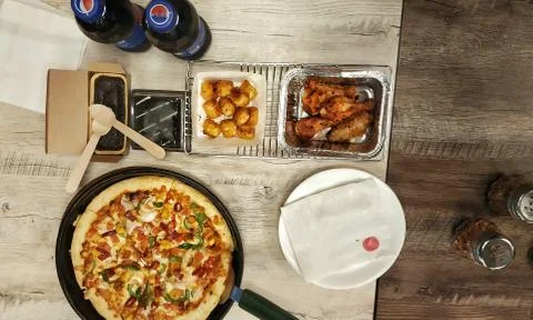 Decorating table with pizza , baked chicken legs and cool drinks bottle Stock Photos