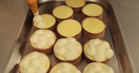 Decorating tartlets with cream using a culinary syringe. Professional confe.. Stock Photos