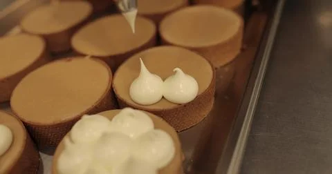 Decorating tartlets with cream using a culinary syringe. Professional confe.. Stock Photos