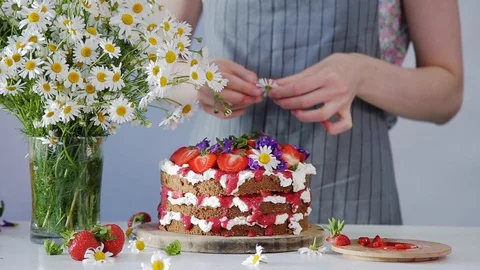 Decorating top of the cake with summer flowers and berries Video stock 102932065