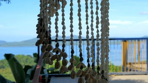 Decoration made of shells close-up stirs under the the light breeze, blue sea on Video stock 109059269