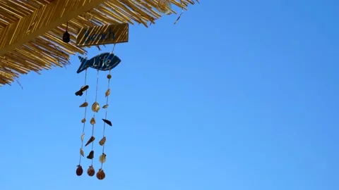 Decorations with sea shells hanging on straw roof of beach bar with blue Stock Footage 137634394
