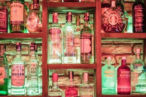 Decorative Bar Shelf Featuring Assorted Bottles of Alcohol in Colorful Lighti Stock Photos